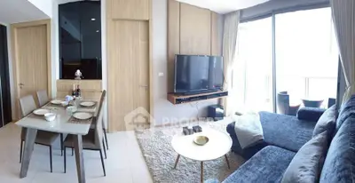 Modern living room with dining area, large TV, and balcony access in a stylish apartment.
