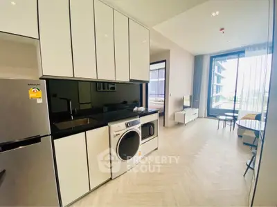 Modern kitchen with sleek cabinets and built-in washing machine in open layout apartment.