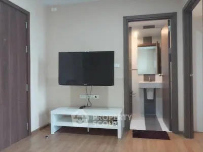 Modern living room with wall-mounted TV and view into bathroom