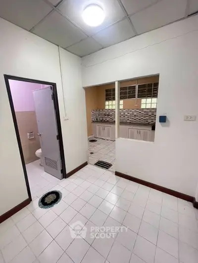 Spacious entryway leading to a modern kitchen and bathroom in a cozy apartment.