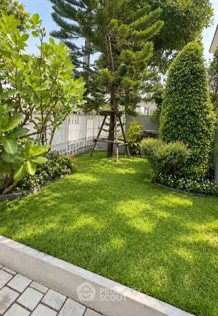 Lush green garden with manicured lawn and trees in a serene residential setting.