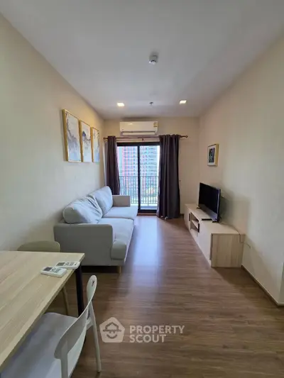 Modern living room with cozy sofa, TV, and balcony view in a stylish apartment.