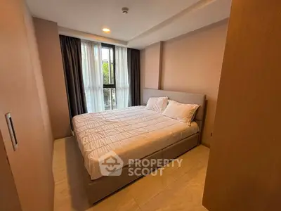 Cozy bedroom with large window and modern furnishings in a stylish apartment.