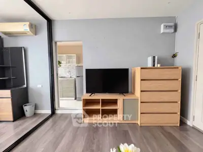 Modern living room with sleek TV stand and wooden dresser, featuring stylish decor and open layout.