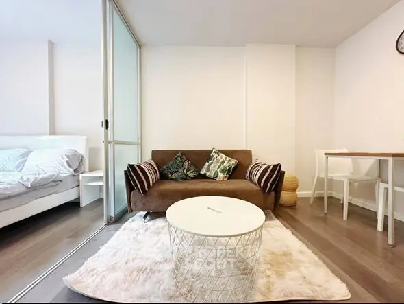 Modern living room with cozy sofa, stylish coffee table, and adjacent bedroom in open-plan apartment.