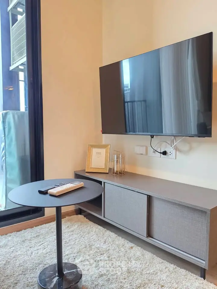 Modern living room with wall-mounted TV and sleek furniture in a cozy apartment setting.