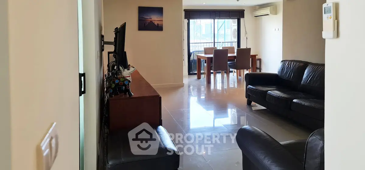 Spacious living room with modern furniture and dining area, featuring large windows for natural light.