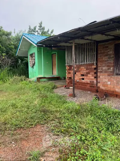 Charming rustic house with brick and green exterior, surrounded by lush greenery, perfect for nature lovers.