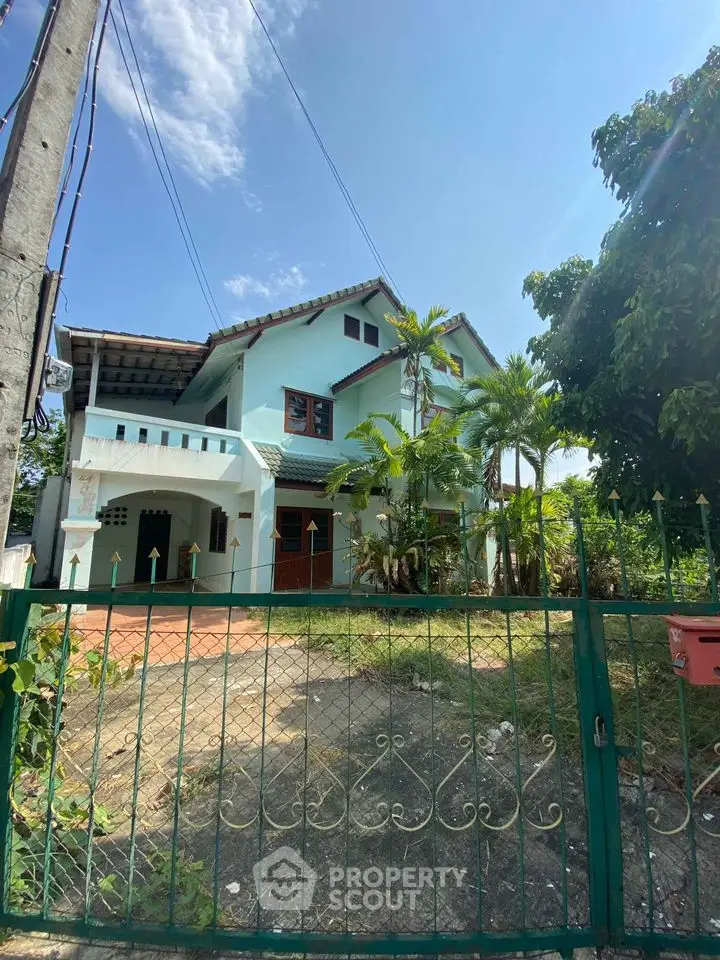 Charming two-story home with lush greenery and a spacious front yard, featuring a large balcony and traditional architectural details.