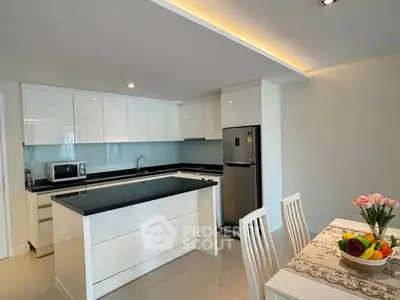 Modern kitchen with sleek white cabinets and dining area, featuring a fruit bowl centerpiece.