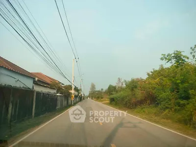 Scenic suburban road with houses and lush greenery, perfect for tranquil living.