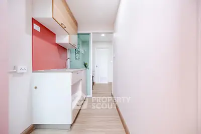 Modern compact kitchen with sleek cabinetry and vibrant accent wall in a cozy apartment.