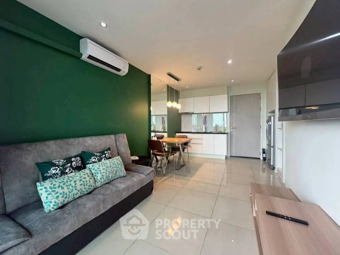 Modern living room with green accent wall and open kitchen layout