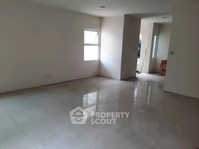 Spacious empty room with glossy tiled floors and natural light