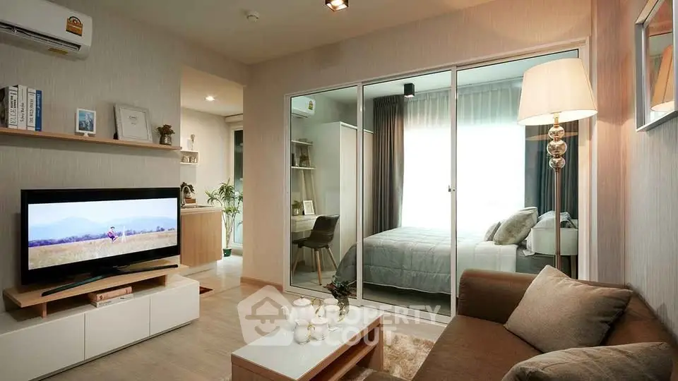 Modern living room with cozy sofa, TV, and view into stylish bedroom through glass doors.