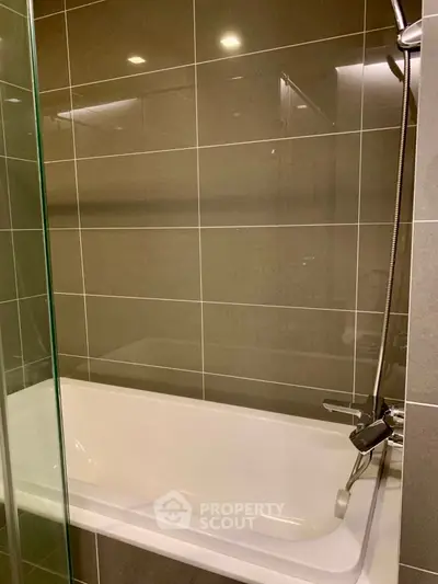 Modern bathroom with sleek bathtub and glass shower enclosure.