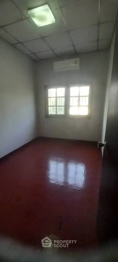 Cozy empty room with red-tiled floor and window, perfect for customization.