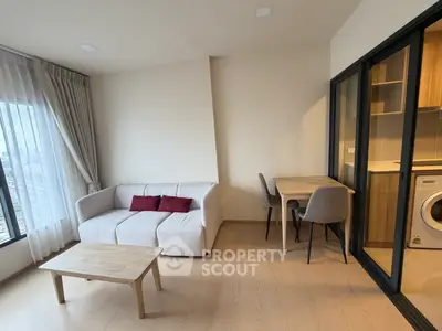 Modern living room with cozy sofa, dining table, and washing machine in sleek apartment.