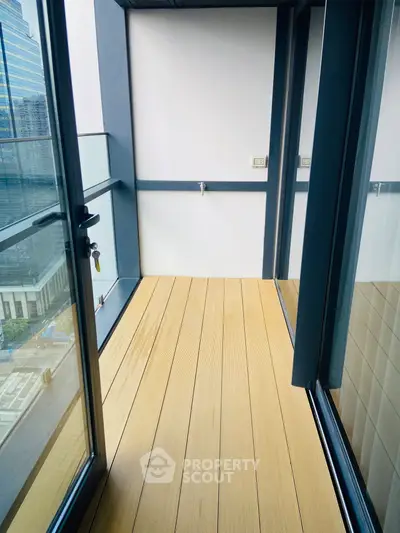 Modern balcony with wooden flooring and glass railing offering city views.