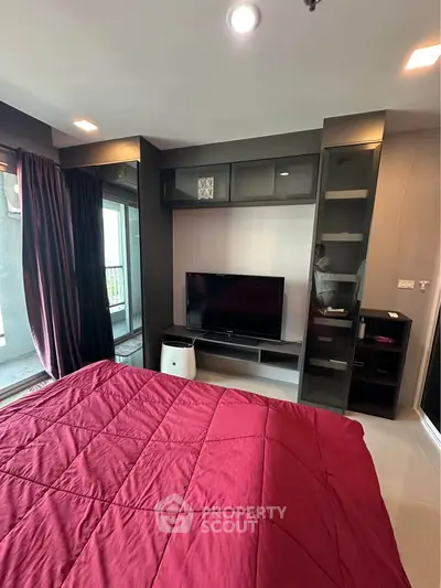 Modern bedroom with sleek built-in entertainment unit and large window for natural light.