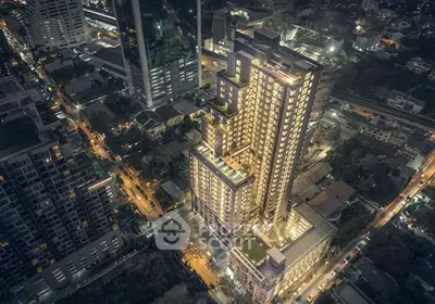 Stunning aerial view of illuminated modern high-rise building in vibrant cityscape at night.