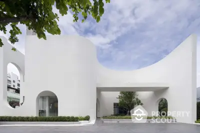 Modern architectural building with unique curves and minimalist design under a clear blue sky.