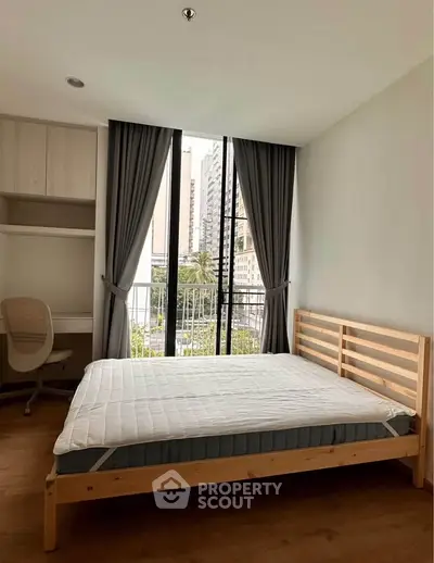 Modern bedroom with large window and city view, featuring a minimalist bed and study area.