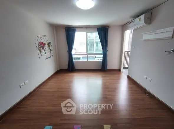 Spacious empty room with wooden flooring and large window view