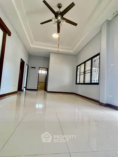 Spacious living room with ceiling fan and large windows, perfect for family gatherings.