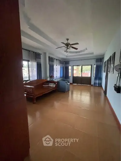Spacious living room with ceiling fan and large windows for natural light.