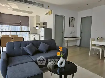 Modern living room with sleek furniture and open kitchen in a high-rise apartment.