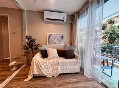 Cozy living room with air conditioning and balcony access, featuring modern decor and natural light.