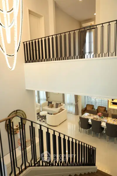 Luxurious open-plan living and dining area with elegant staircase and modern chandelier