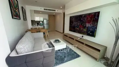 Modern living room with stylish furniture and large TV in open layout apartment.