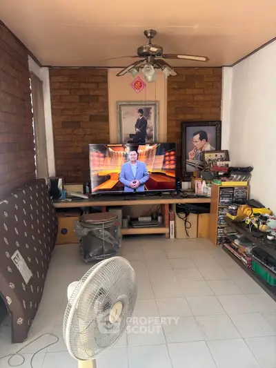 Cozy living room with TV, fan, and eclectic decor in a compact space.