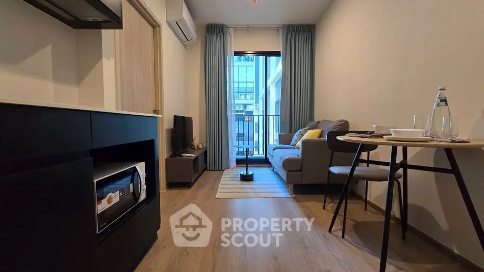 Modern living room with balcony view, featuring cozy seating and stylish decor in a compact apartment.