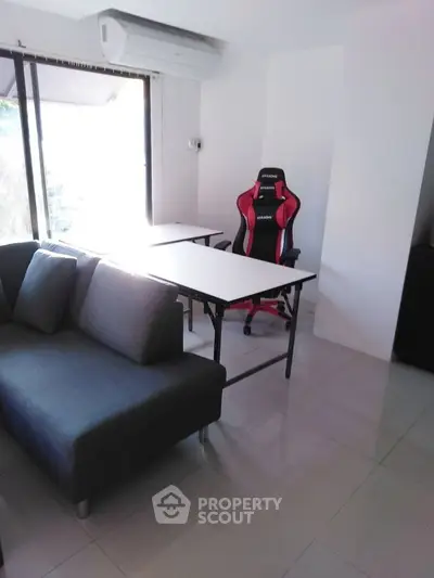 Modern living room with sleek furniture and gaming chair, perfect for relaxation and entertainment.
