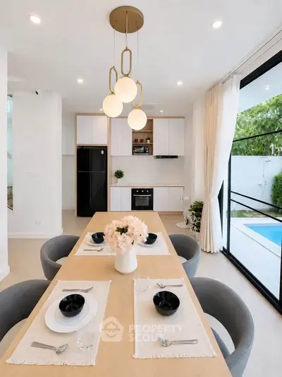 Modern dining area with elegant table setting, open kitchen, and pool view, perfect for stylish living.