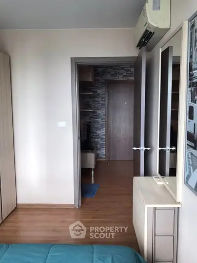 Modern bedroom with wooden flooring and air conditioning, featuring a stylish stone accent wall in the hallway.