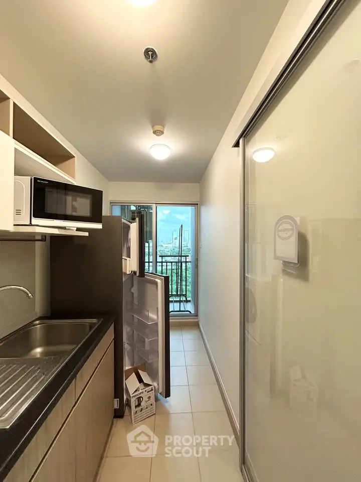 Compact kitchen with modern appliances and balcony view in urban apartment