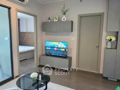 Modern living room with sleek furniture and TV, adjacent to a cozy bedroom.