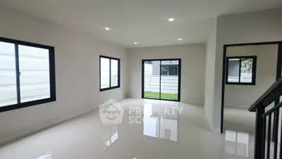 Spacious modern living room with large windows and garden view, perfect for family gatherings.