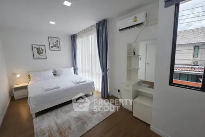Modern bedroom with large window, air conditioning, and stylish decor in a cozy apartment.