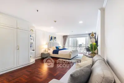 Spacious bedroom with elegant decor and city view, featuring a cozy seating area and stylish furnishings.