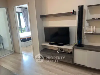 Modern living room with sleek TV setup and view into a cozy bedroom