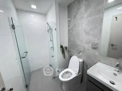 Modern bathroom with glass shower and sleek fixtures in contemporary apartment.