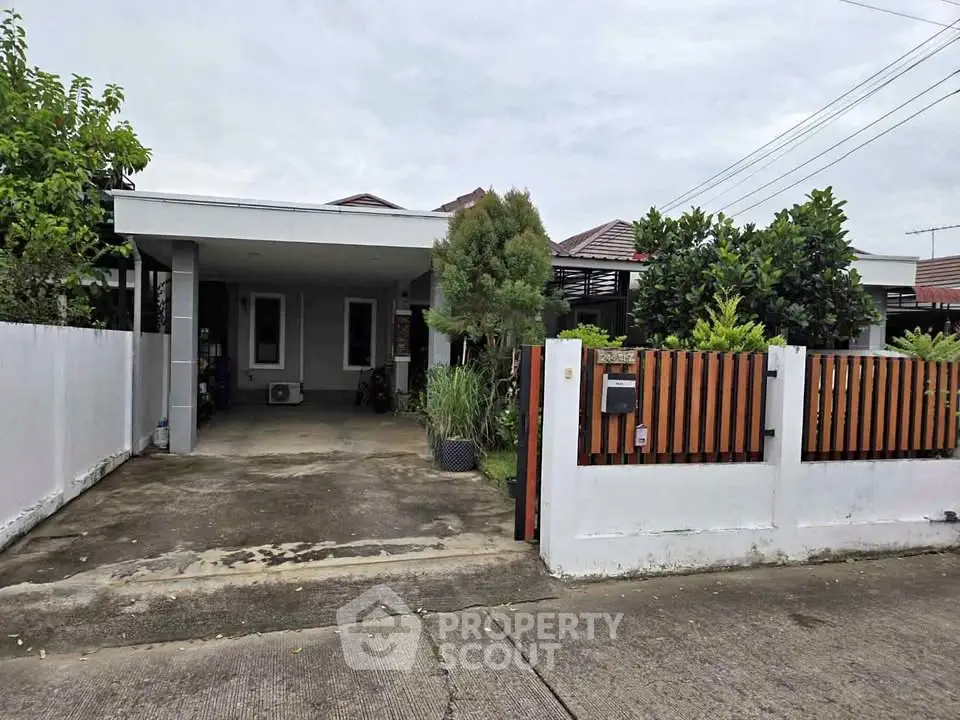 Charming single-story house with driveway and lush greenery in a serene neighborhood.