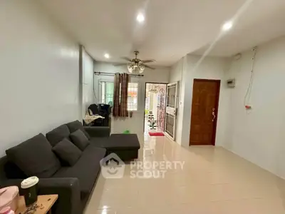 Spacious living room with modern sofa and ceiling fan, perfect for relaxation and entertainment.
