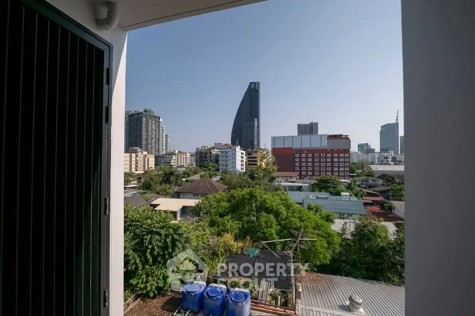 Stunning cityscape view from a balcony with lush greenery and modern skyscrapers.