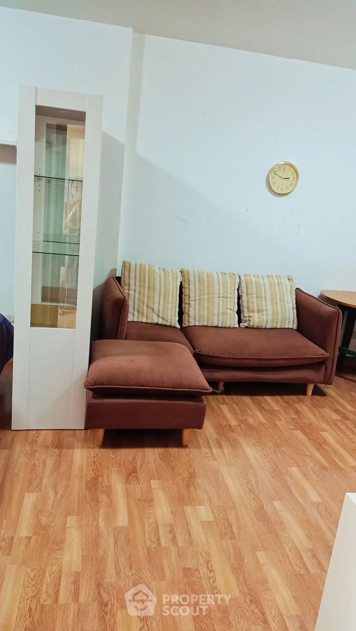 Cozy living room with brown sofa and wooden flooring, perfect for relaxation.